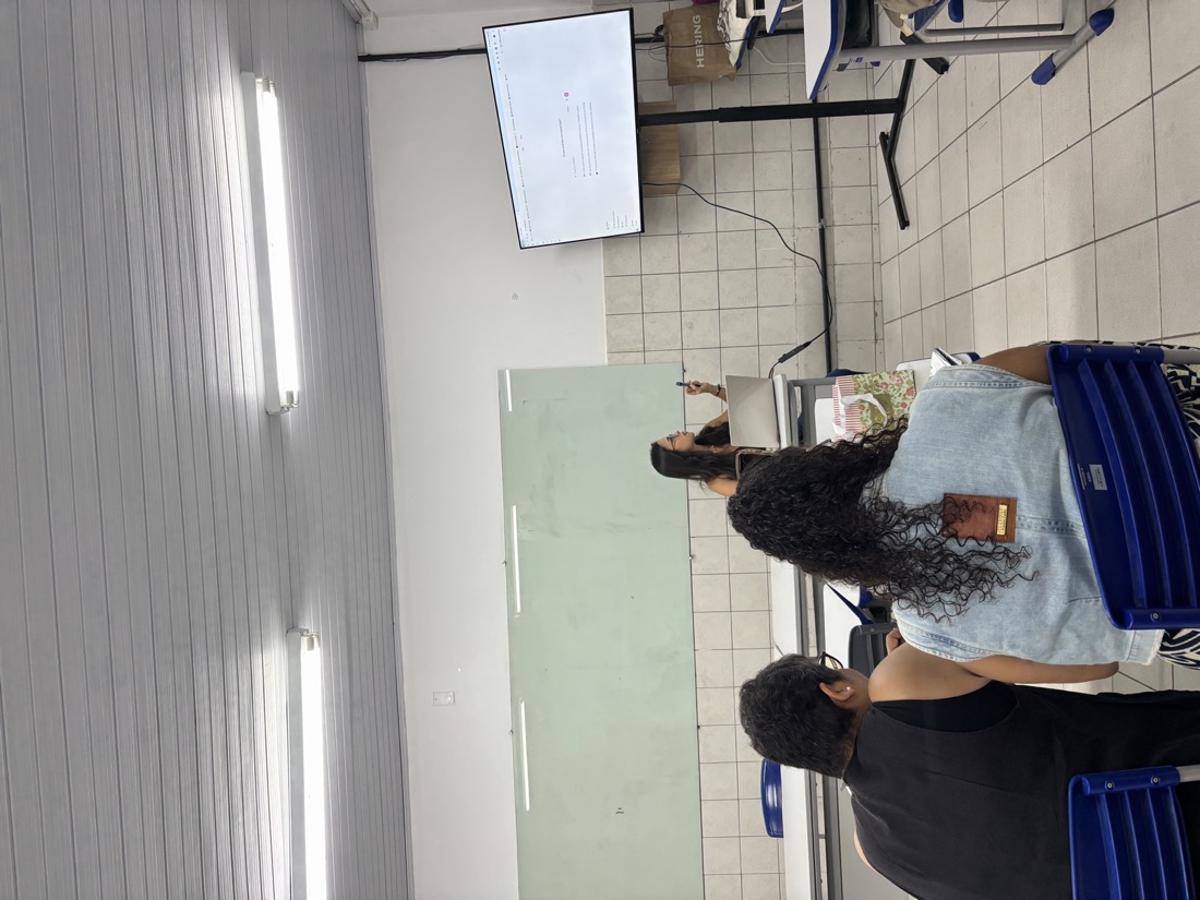 Raquel Galvão ministrando o curso IA na Prática Docente, apresentando numa tela pra um grupo de professores