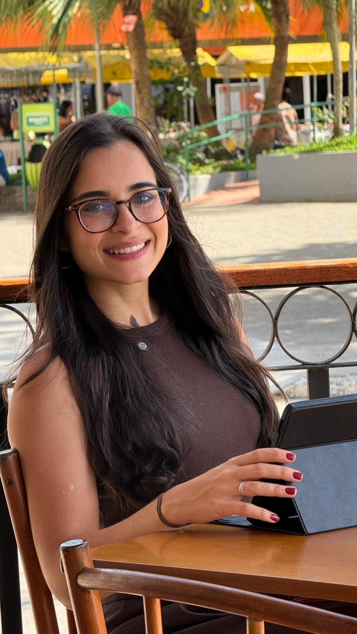 Raquel Galvão sorrindo, sentada a uma mesa de madeira ao ar livre, com um tablet